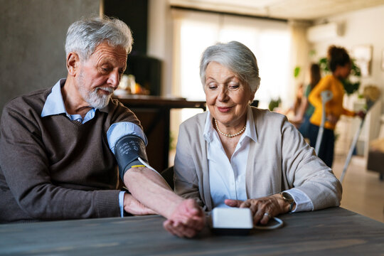 Happy Senior Couple Measuring Blood Pressure At Home