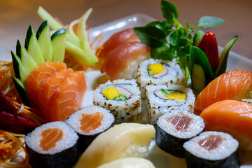 Japanese food mix including sushi and sashimi on white plate.