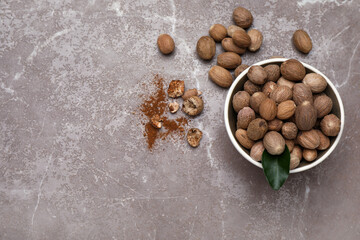 Bowl with nutmeg seeds on grey table, flat lay. Space for text