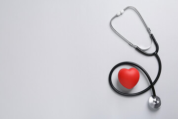 Stethoscope, red decorative heart on grey background, flat lay with space for text. Cardiology...