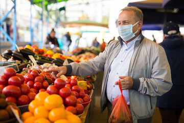 Middle aged man in mask buying tomatoes