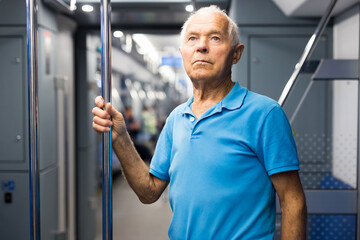 Senior man standing inside subway train