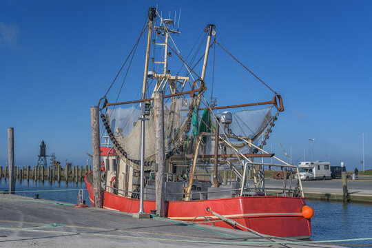 Fischerboot im Hafen von Dorum-Neufeld mit Leuchtturm im Hintergrund