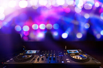 Fototapeta na wymiar DJ console mixer at a nightclub, people blurred background dancing.