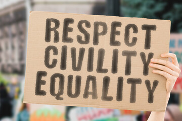 The phrase " Respect civility equality " on a banner in men's hands with blurred background. Racial. Together. Truth. Unity. Us. United. Equity. Activist. Recognition. Fairness. Fair. Integrity. Love