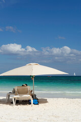 Rear view of a tourist sitting on a sunbed on the beach against the clear blue sky in Mexico