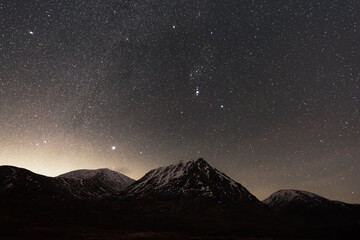 Glen Etive astrophotography with the Milky Way and Orion rising above a snowy mountain peak