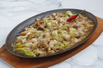 Freshly made Filipino food called Pork Sisig or chopped pork served in a hot plate
