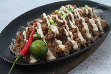 Freshly made Filipino food called Pork Sisig or chopped pork served in a hot plate
