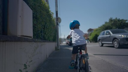 Child riding bicycle outside in urban street little boy rides bike on sidewalk