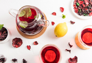 tea background. teapot with fruit and herbal tea, two glass cups on a white table with roses and lemon fruit. vitamin tea.