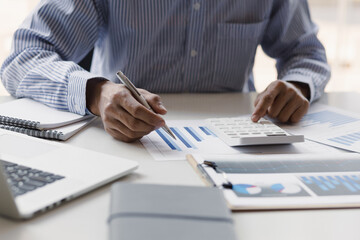 Working businessman is pointing on documents, financial charts, analysis using calculator and personal financial planning.