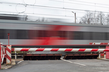 A clear electric train against the background of a closed barrier, road safety.