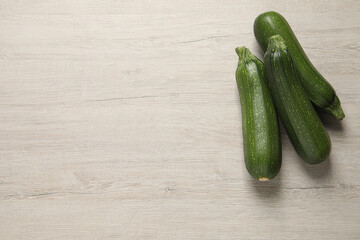 Raw ripe zucchinis on white wooden table, flat lay. Space for text