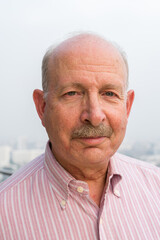 Portrait of happy senior man looking at camera in city at rooftop