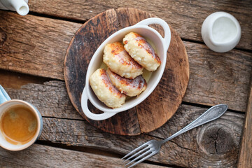 Cottage cheese pancakes with condensed milk. Side view, wooden background. Syrnik