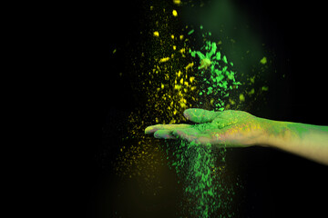 Holi festival of colors. Holi powder splatted in hands on black background