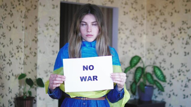 Upset Sad Ukrainian female with a flag protesting war conflict raises banner with inscription message text No War. Crisis, peace, stop aggression,  Russian war invasion. Stop War in Ukraine. Pray 