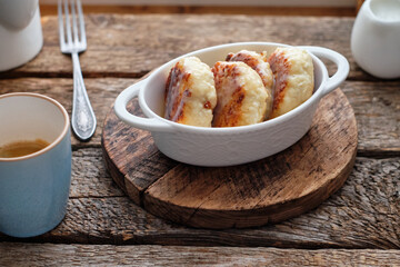 Cottage cheese pancakes with condensed milk. Side view, wooden background. Syrnik