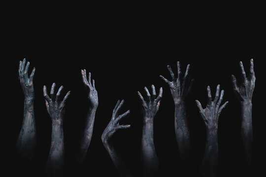many scary and creepy zombie hands raising from darkness