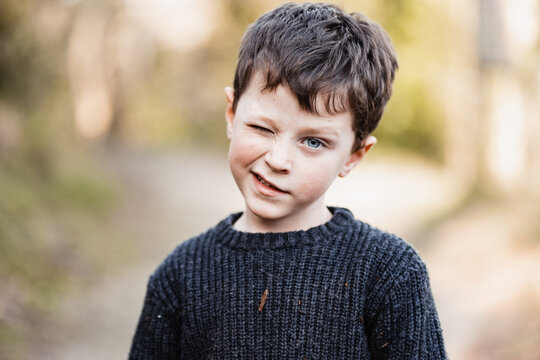 Boy in warm sweater winking at camera