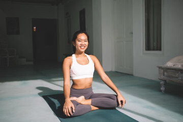Asian girl practicing yoga at spacious home
