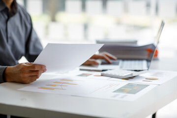
Close up of accountant working and analyzing financial reports project accounting with chart graph and calculator in modern office : finance and business concept.