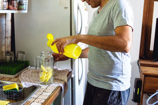 man at home serving water in a jug with lemon slices