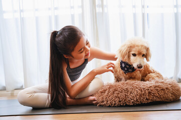 Little Girl in sportswear playing with her dog on a yoga mat in the living room at home. New normal concept.