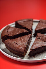 Chocolate Flourless Cake on red background. Soft chocolate gÃ¢teau or Brownie cake. Selective focus