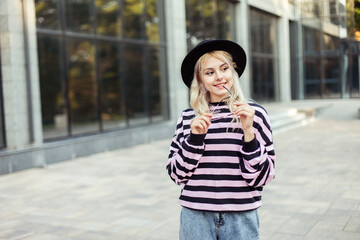 Fototapeta premium Portrait of a young charming woman in a sweater and hat outdoors