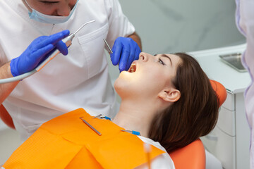 Male dentist examines the oral cavity of a female patient in a dental clinic. Visit to the dentist. Dental treatment