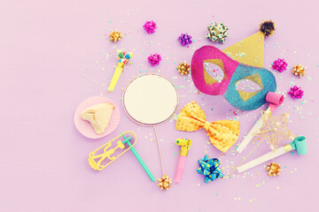 Purim celebration concept (jewish carnival holiday) over purple wooden background