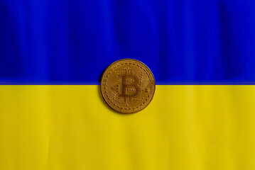 Bitcoin on the background of the Ukrainian flag. The concept of the cryptocurrency market against the backdrop of the war in Ukraine