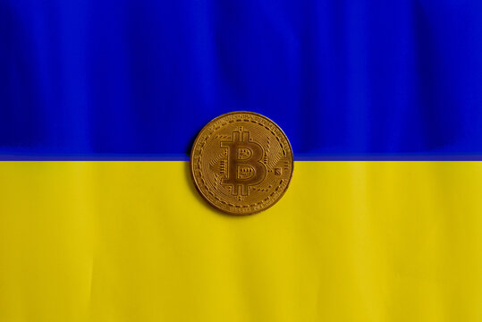 Bitcoin on the background of the Ukrainian flag. The concept of the cryptocurrency market against the backdrop of the war in Ukraine - Powered by Adobe