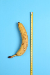 Banana with a ruler on a light blue background. Top view. Sex concept