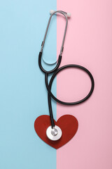 Stethoscope with heart on blue pink background. Cardiovascular disease diagnosis, love concept. Top view