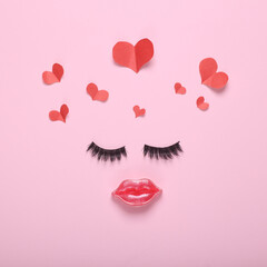 False eyelashes and lips in the shape of a face and hearts on a pink background. Beauty, love...