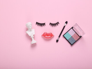 False eyelashes with lips in the shape of a face and eyeshadow palette, venus bust on pink background. Beauty minimal still life. Flat lay