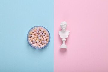 VEnus bust and balls of powder on blue-pink pastel background. Beauty flat lay