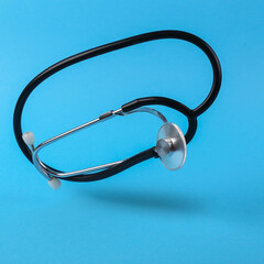 Levitating medical stethoscope on blue background with shadow