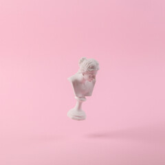 Levitating Antique Plaster bust of venus on pink background with shadow. Conceptual pop. Minimal still life photography