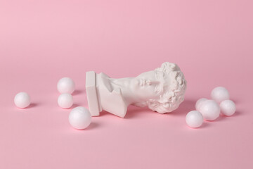 Antique bust of David with white balls on a pink background. Conceptual pop. Minimal still life....