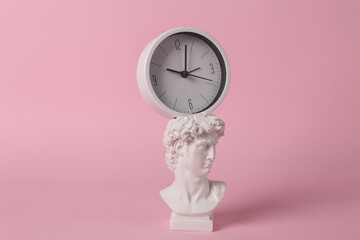 Antique David bust with clock on pink background. Conceptual pop. Minimal still life. Creative idea