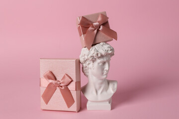 David Bust with gift boxes on pink background. Minimal holiday still life