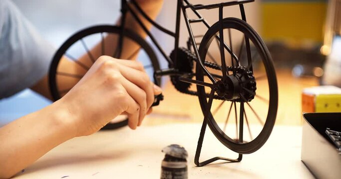 Teenage boy working on bicycle model. Sitting in his room, profile view, close up