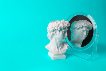 Bust of David admires himself looking in a mirror on turquoise background. Narcissism. Minimal...