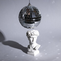 Bust of David with a disco ball on gray background with shadow. Minimal party concept. Creative...