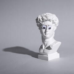 David bust with goggling eyes on gray background. Minimal still life