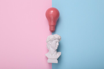 David bust with light bulb on pink blue background. Creative idea. Minimal still life. Flat lay....